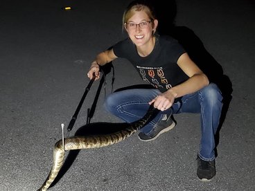 woman smiling at camera while holding a snake