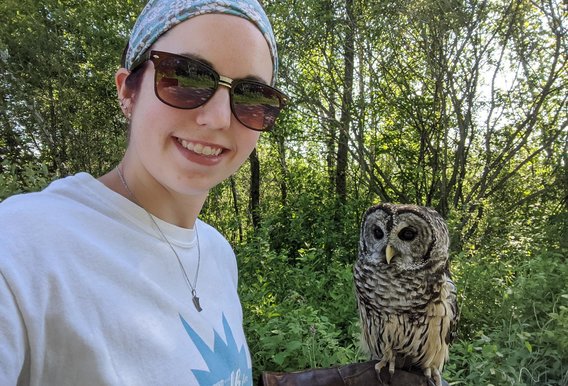 Woman wearing sunglasses with an owl perched on her hand