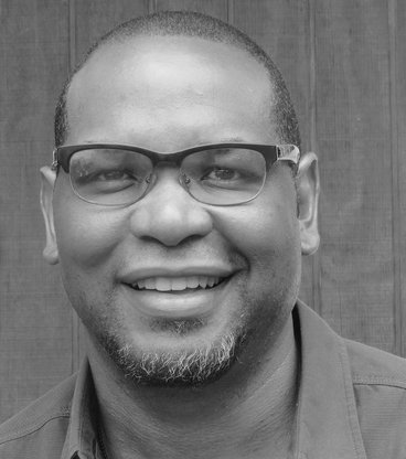 black and white image of smiling black man with glasses - Dr Lanham