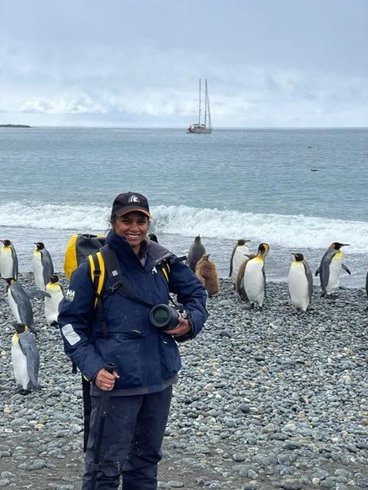 smiling woman on Antarctic shore with penguins