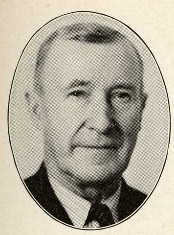 black and white photo portrait of a white man in suit and tie